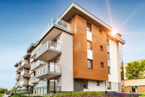Modernes Wohngebäude mit Balkonen, Holzfassade und sonniger Außenansicht.